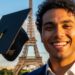 A close-up image of a student smiling, holding a graduation cap, with the Eiffel Tower in the background.